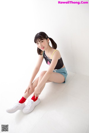 A young woman in a black top and blue shorts posing for a picture.