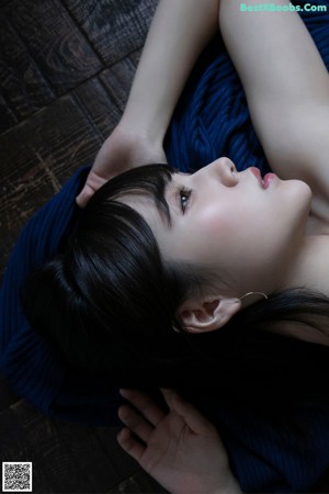 A naked woman laying on a wooden floor.