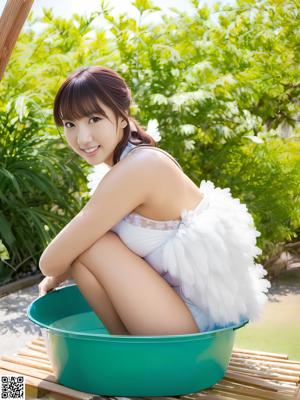 A naked asian woman sitting on a bed with her legs crossed.