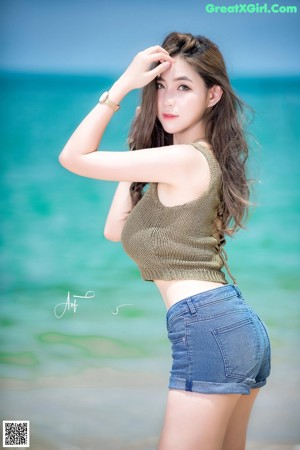 A woman sitting on a rock by the ocean.