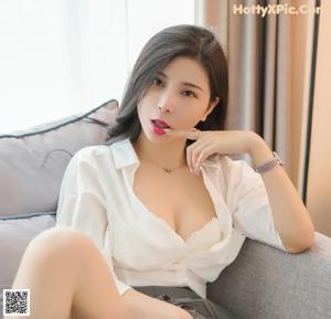 A woman in a white shirt and gray skirt posing for a picture.