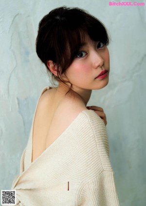 A woman in a white dress leaning against a wall.
