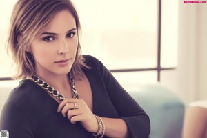 A beautiful young woman sitting on a bed with her legs crossed.