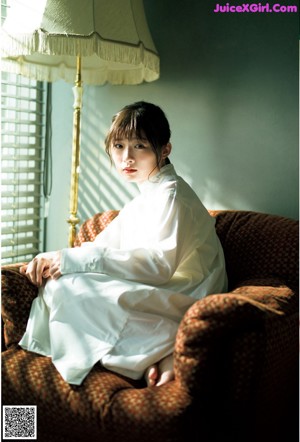 A woman in a white shirt is looking at the camera.