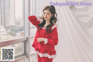 A woman in a pink robe sitting on a window sill.
