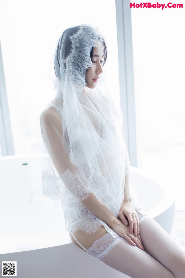 A woman in a white lingerie sitting on a bathtub.