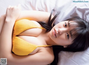 A woman in a pink bikini sitting on a bed.