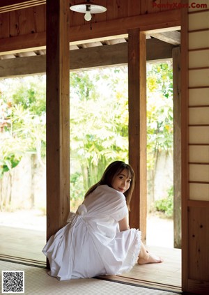 A woman in a yellow dress laying on a bed.