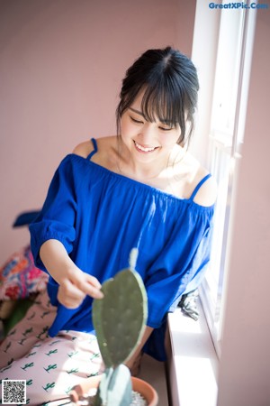A woman sitting on a stool holding two lemons.