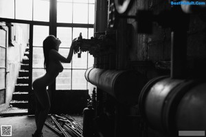 A naked asian woman posing in front of a window.