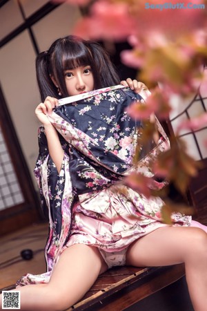 A woman in a kimono sitting on a wooden floor.
