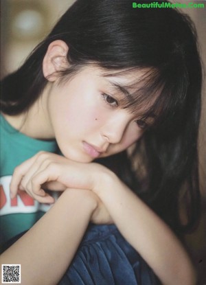 A young woman in a blue dress sitting on the ground.