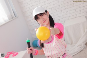 A woman in a pink and white striped outfit holding a microphone.