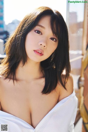 A woman in a white shirt is posing for the camera.