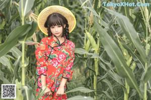 A woman in a straw hat holding a pumpkin in a field.