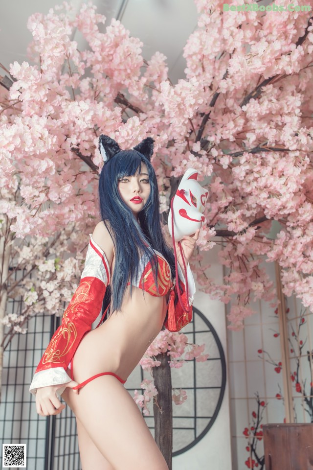 A woman in a red and white outfit holding a cat mask.