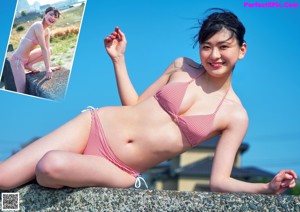 A woman in a red and white striped bikini sitting on a rock.