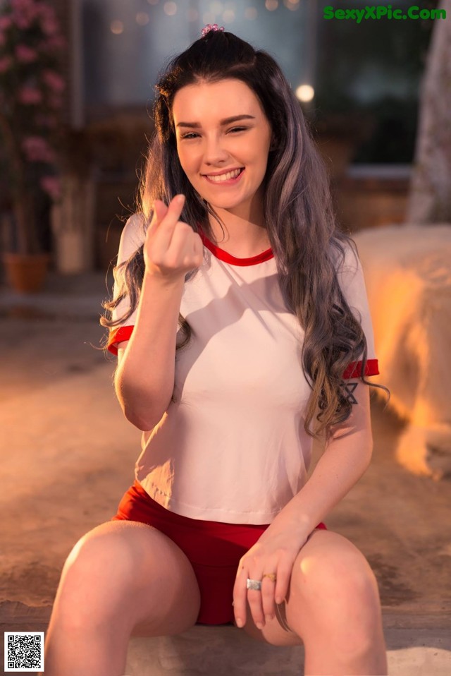 A woman in a white shirt and red shorts posing for a picture.
