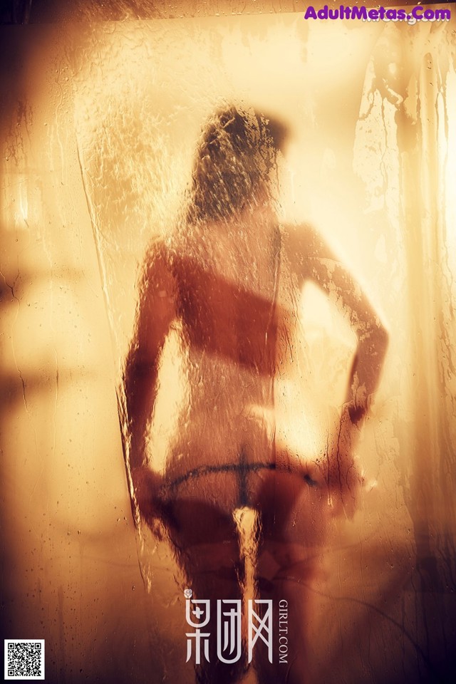 A man standing in front of a window with his back to the camera.