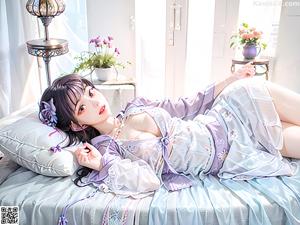 A woman sitting on top of a bed next to a window.