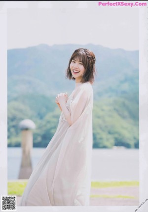A woman in a white shirt leaning against a wall.